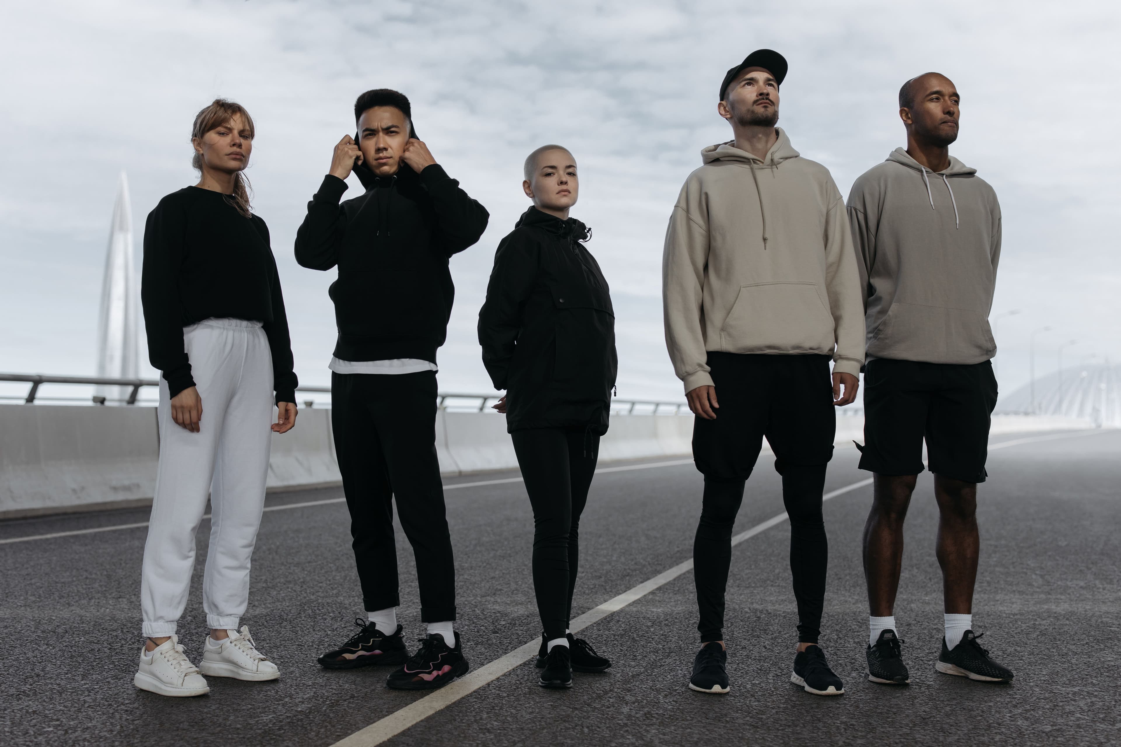 Five people in casual sweatshirts and joggers on a bridge