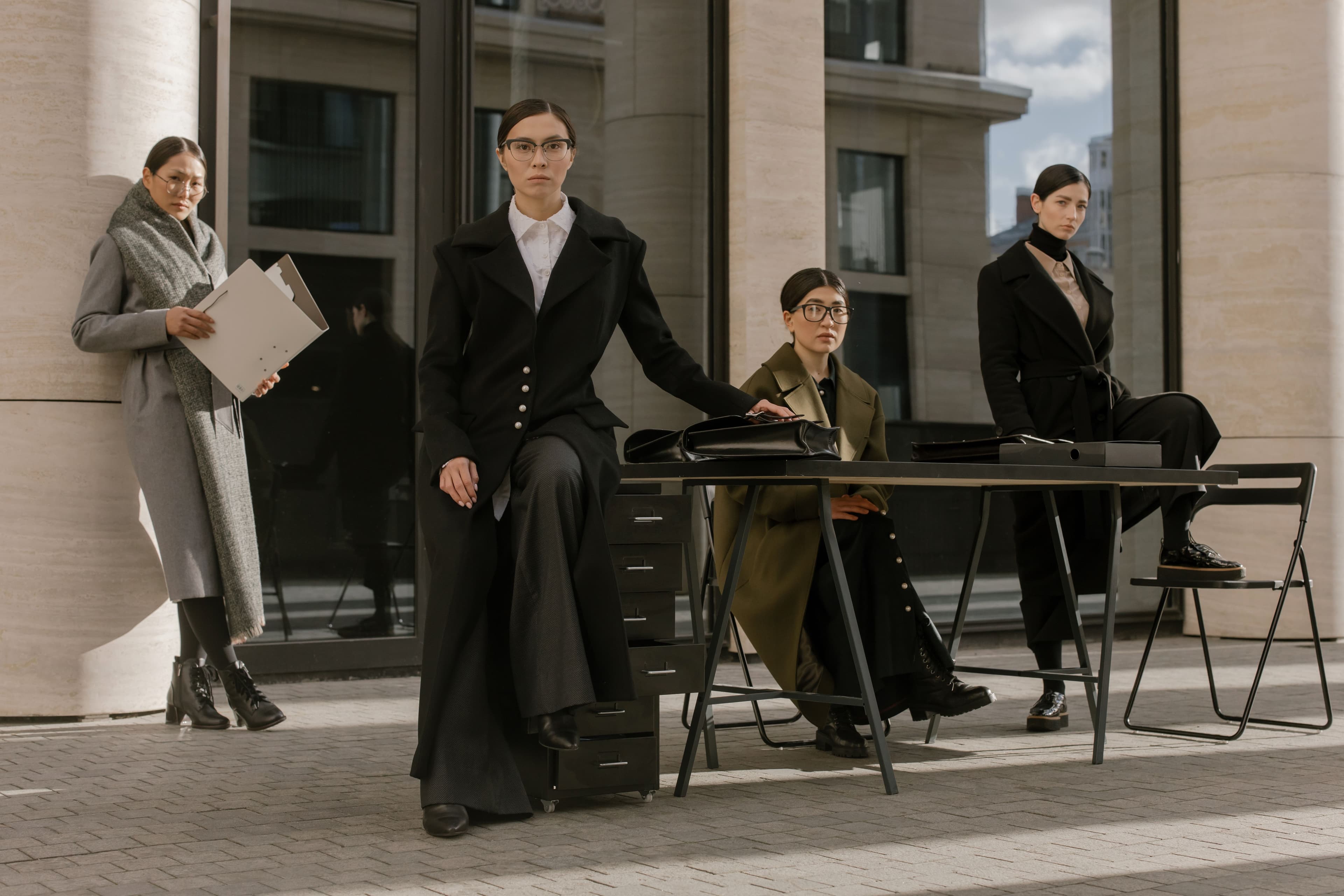 Team in tailored coats and office wear outside a building